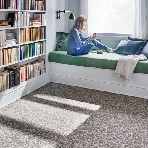Person reading in the window of a room with beige patterned carpet from Flooring Source in the Auburn, MA area