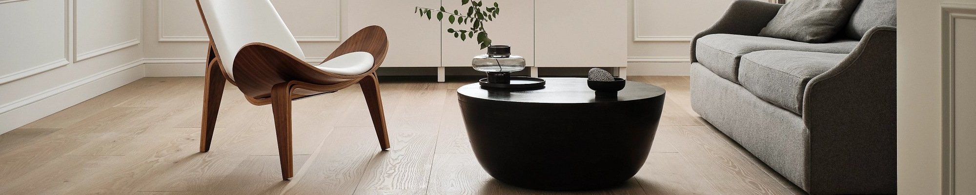 living room with hardwood floor and black coffee table with a plant on it in a glass vase from Flooring Source in the Auburn, MA area